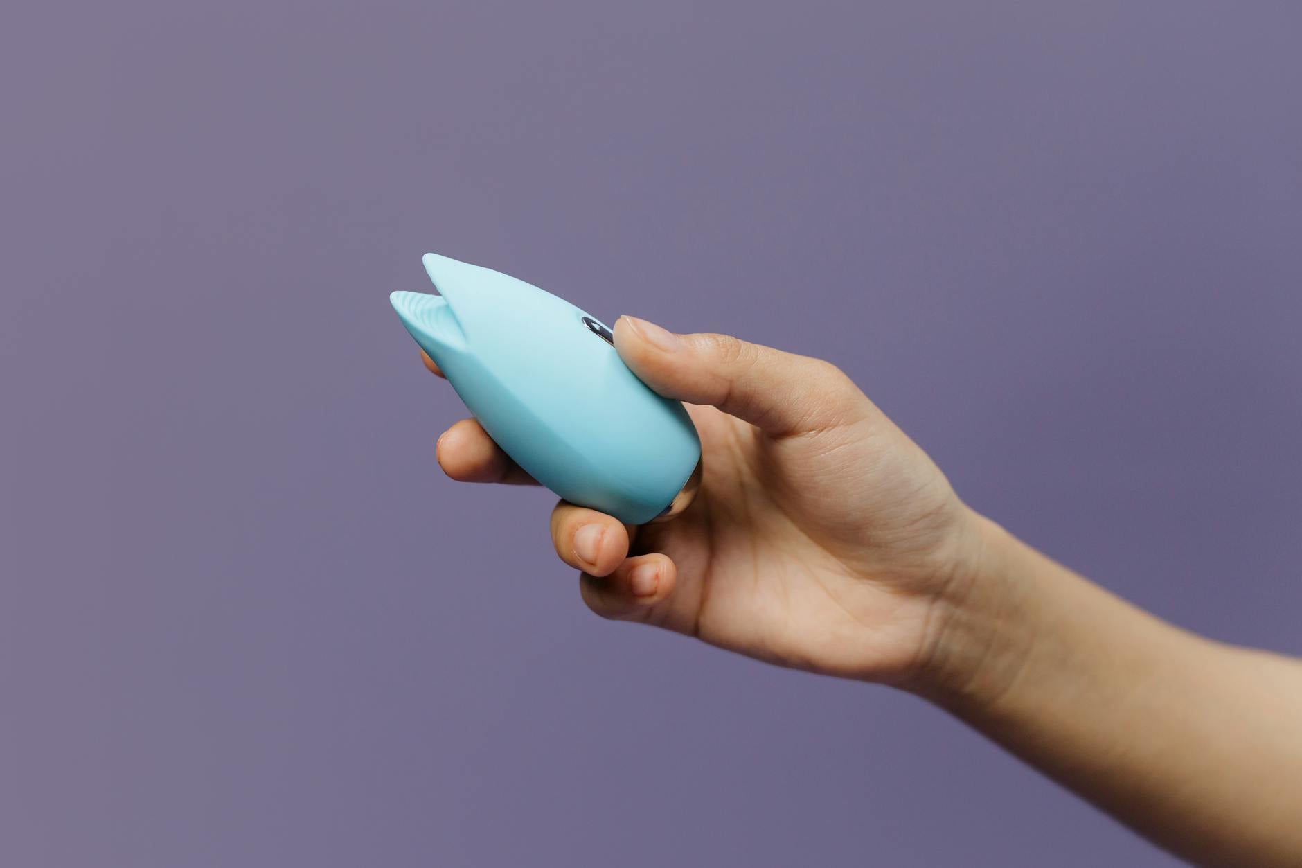 青とピンクのレモンバイブレーターを思慮深い表情で持つ眼鏡をかけた女性
