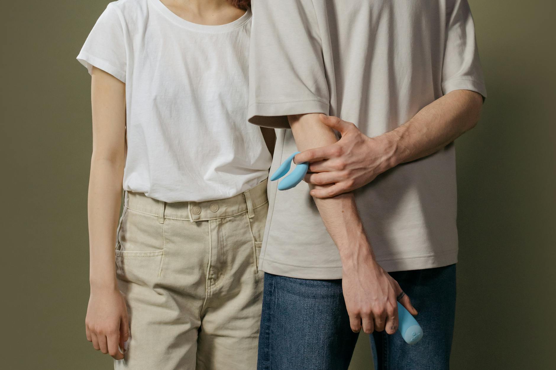 眼鏡をかけた女性が青と ピンクのシリコンバイブレーターを思慮深い様子で持っている写真